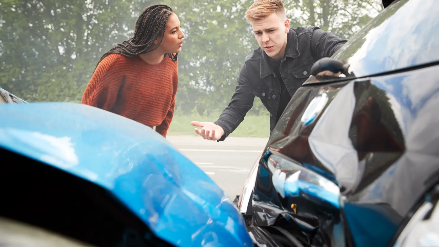 Two drivers examining the damage after a collision